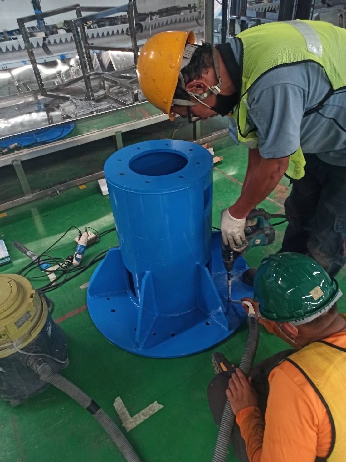 Worker fitting a blue equipment base on a factory floor
