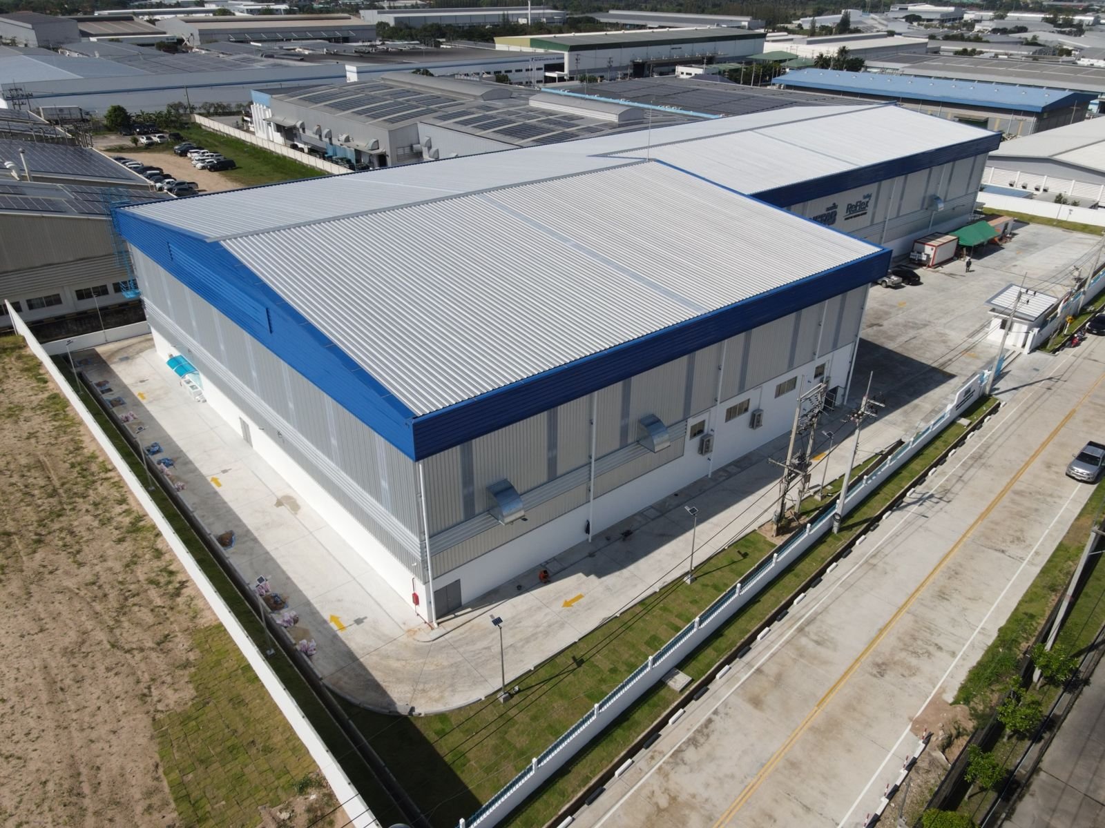 Aerial view of a factory building with blue trim in an industrial area