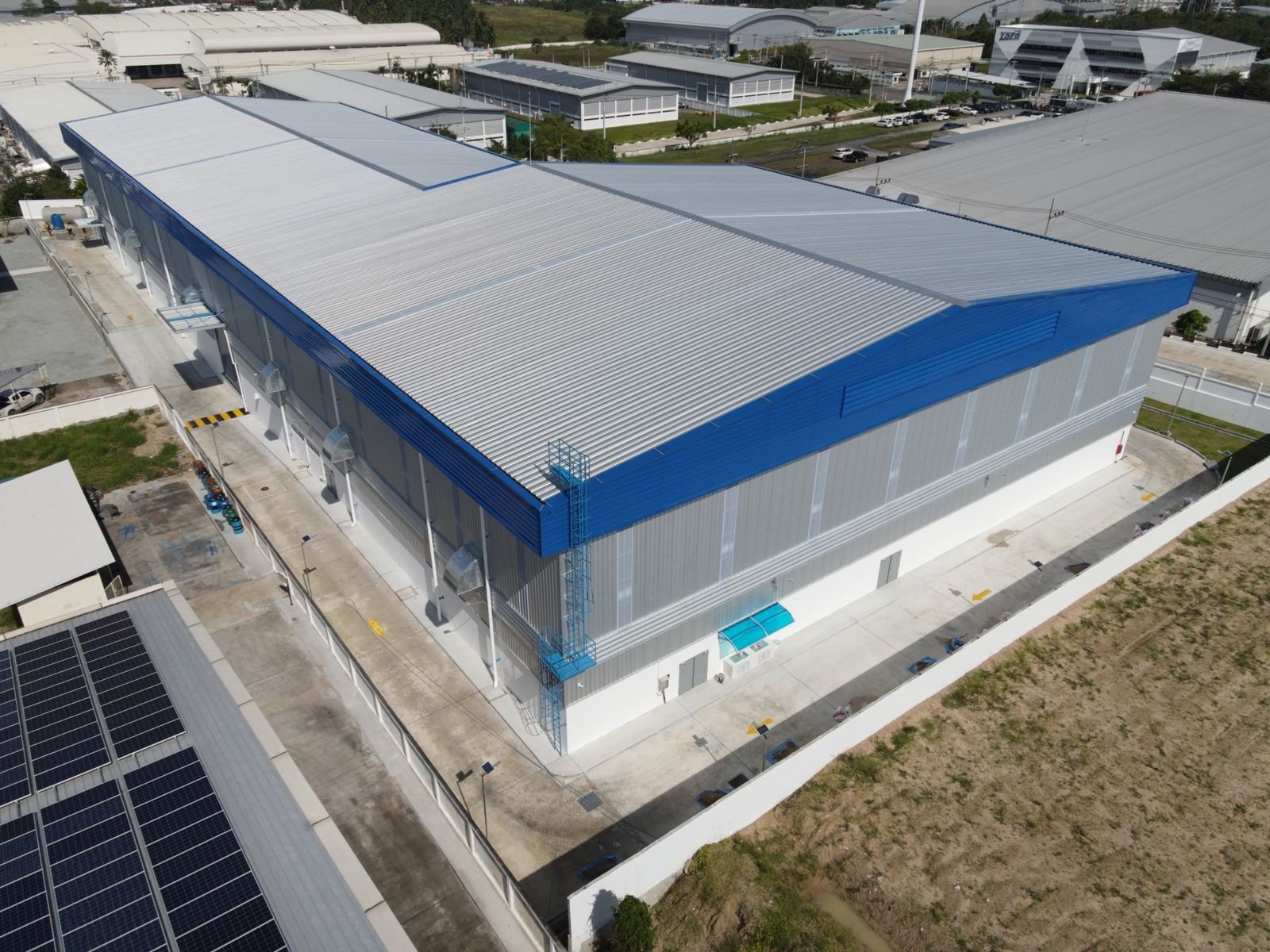 Aerial view of a long factory building with blue trim