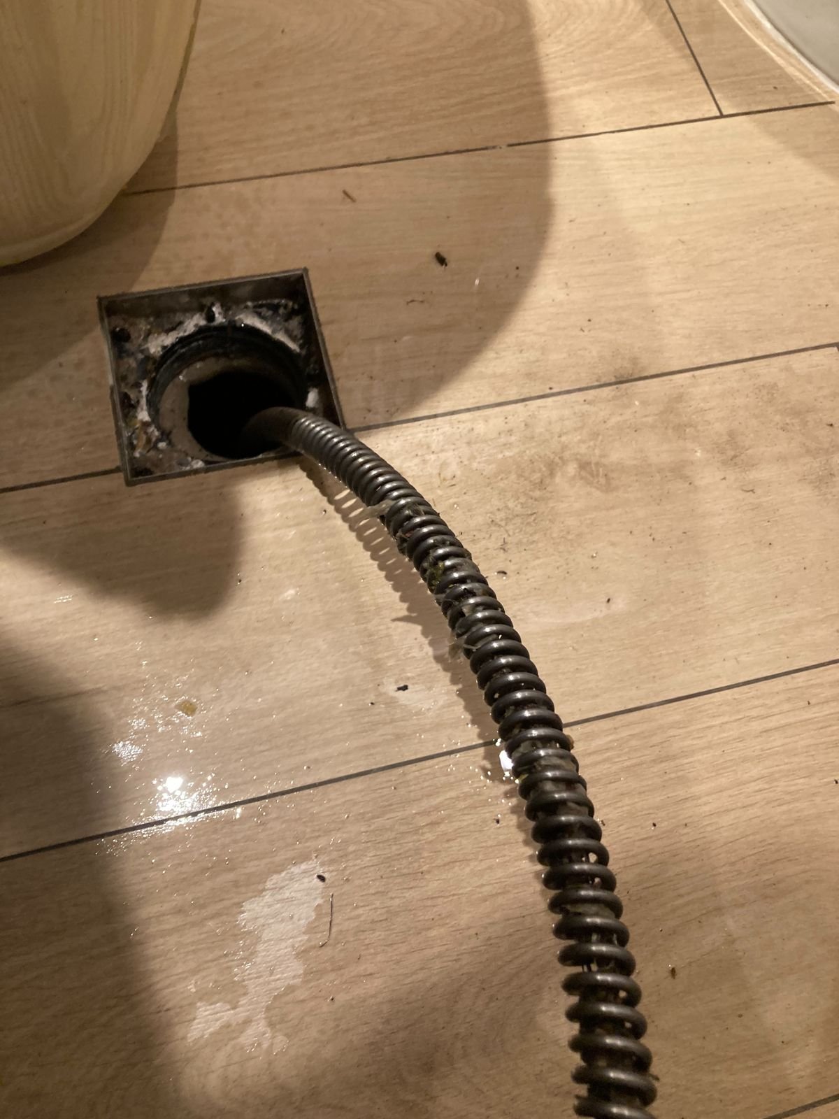 Drain cleaning cable fed into a floor drain