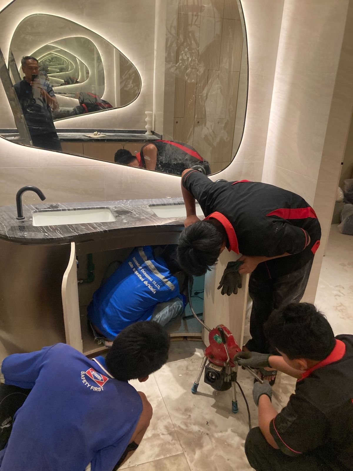 Two technicians clearing a drain in a bathroom