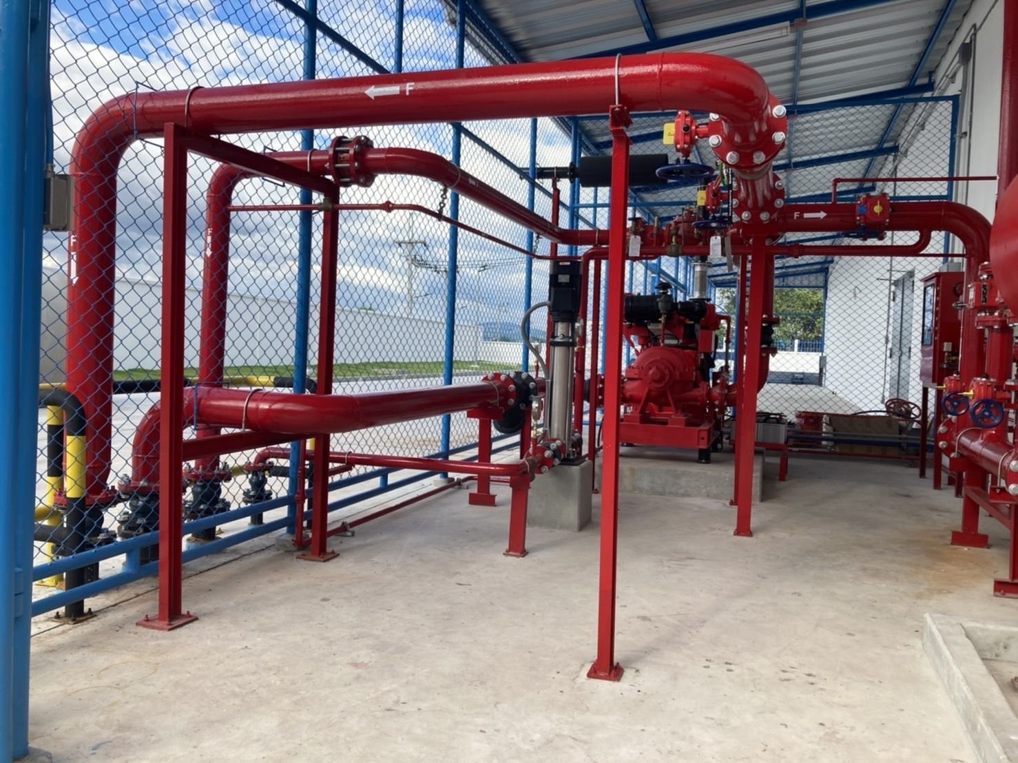 Red fire pipework and valve set inside a mesh enclosure