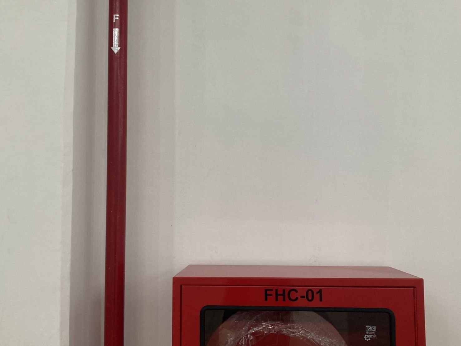 Wall-mounted fire hose cabinet with red riser pipe