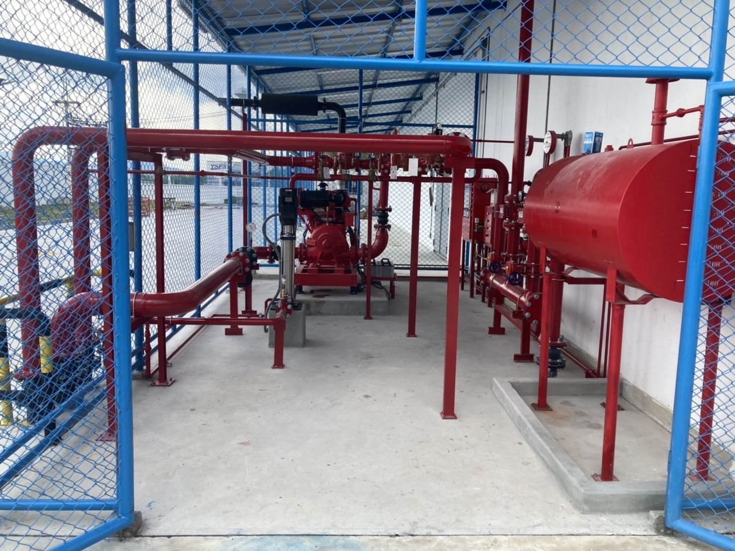 Fire pump room with red pipework, pump sets and a pressure tank